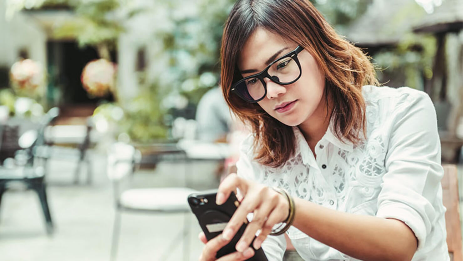 A woman playing mobile phone in outdoor restaurants,Focus on face.