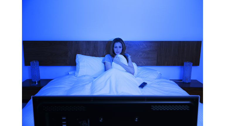 Woman watching television in bed