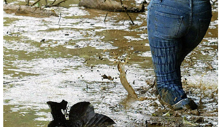 A woman tries to make her way in muddy w