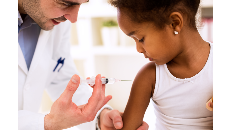 Doctor injecting vaccine to cute african girl