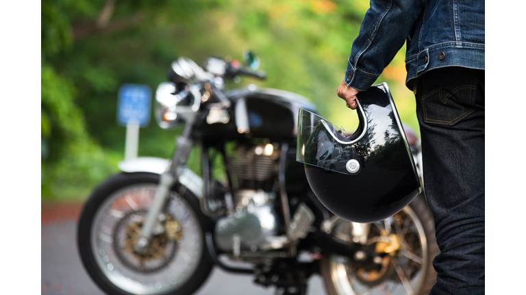 Hand man holding a helmet and  motorcycle blur background.