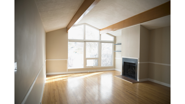 Sunny empty living room with hardwood floors and fireplace