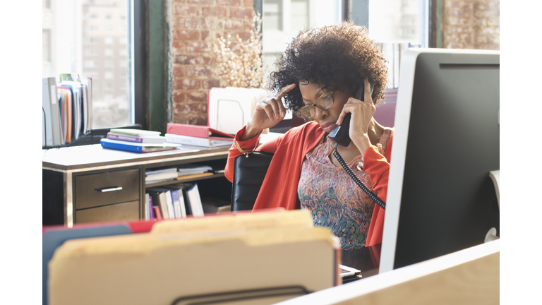 Black businesswoman talking on telephone at desk