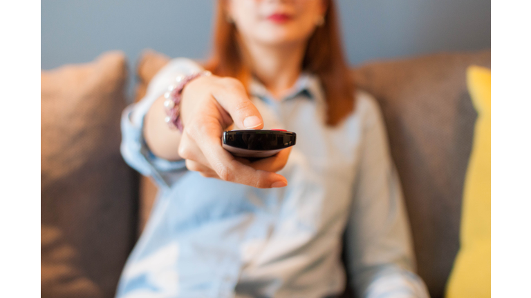 A young woman is holding a television remote control