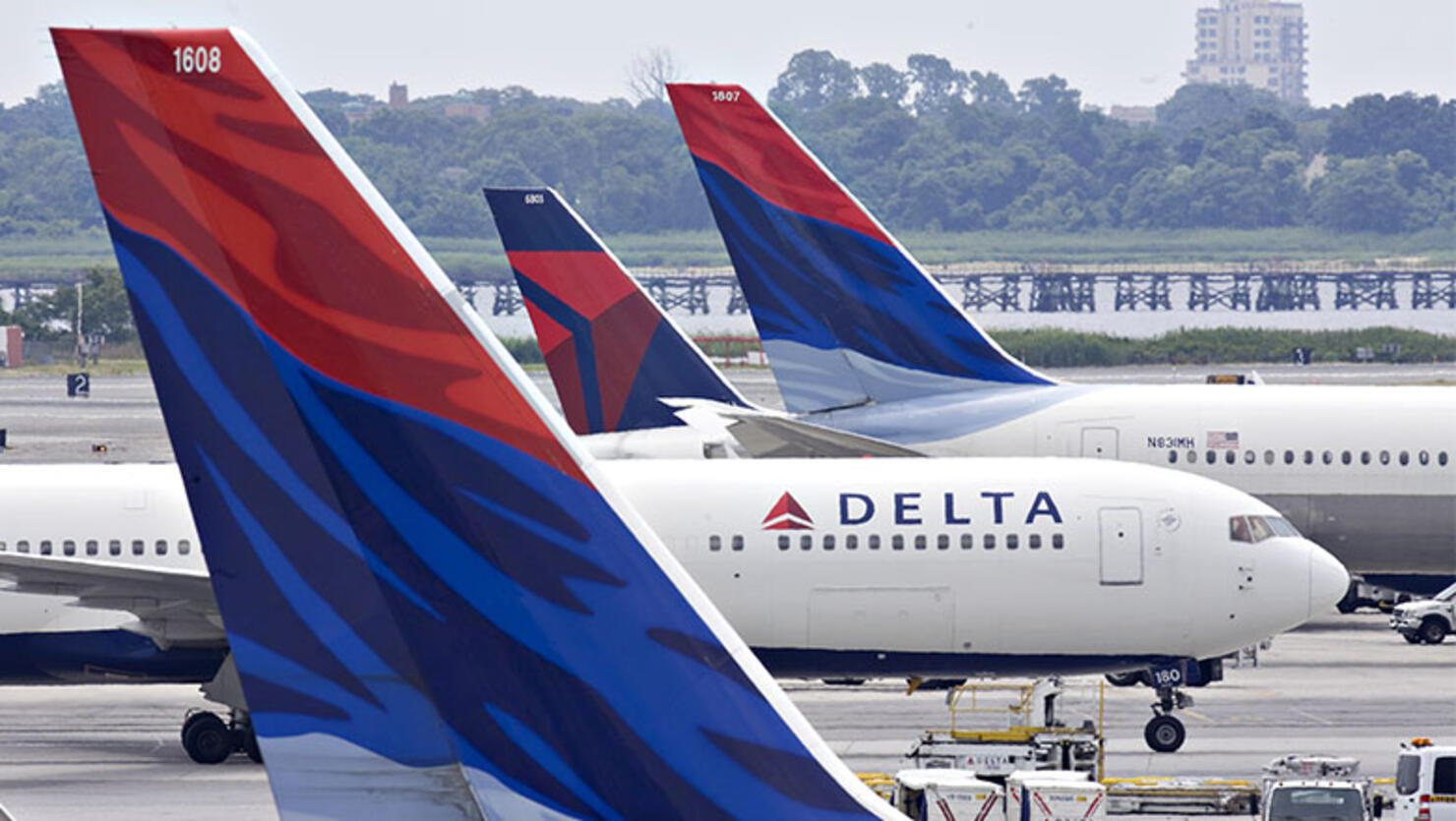 A Delta Air Lines plane taxis toward a gate between other De