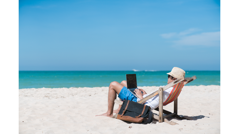 happy business man with laptop working on the beach