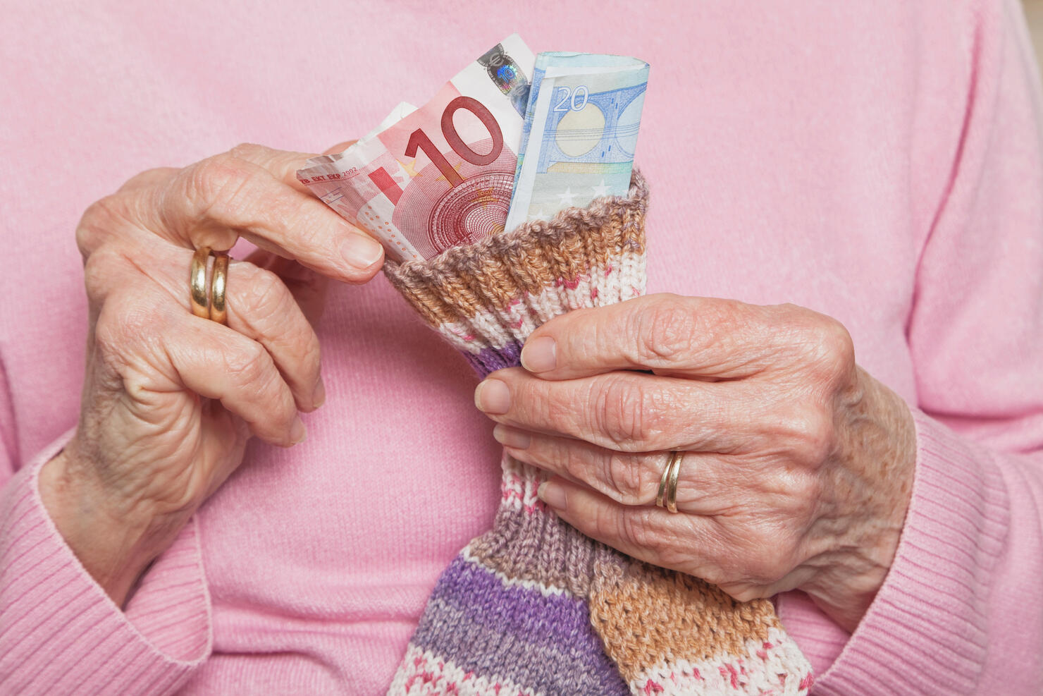 Germany, Senior woman counting money from money sock, mid section