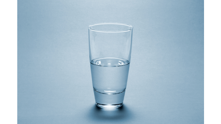 Half full water glass over blue background