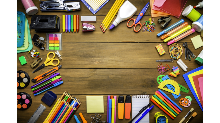 Overhead shot of wood table with frame of school office supplies