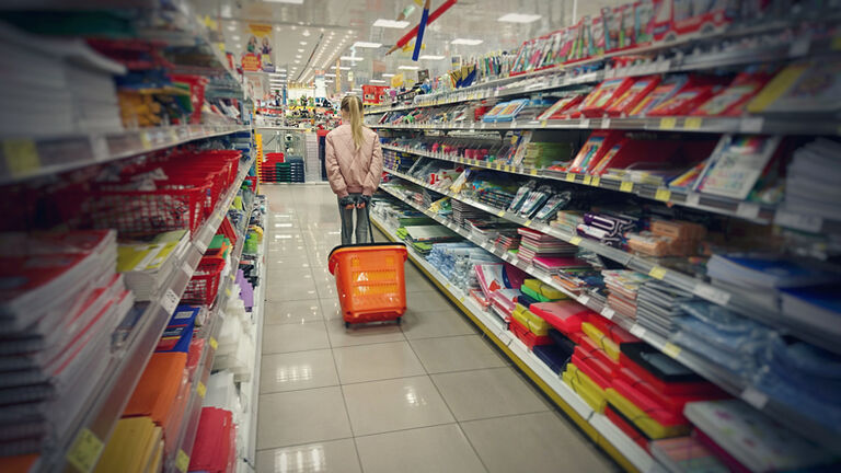Child walking down the aisle of a shop selling 'back to school' stationery