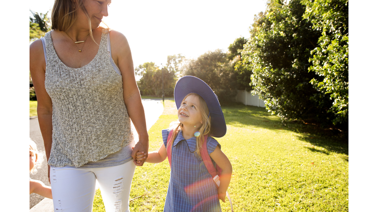 Little girl in uniform walking to school with mum