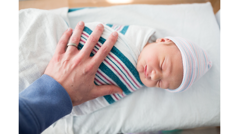 Father Rests Hand on Sleeping Newborn