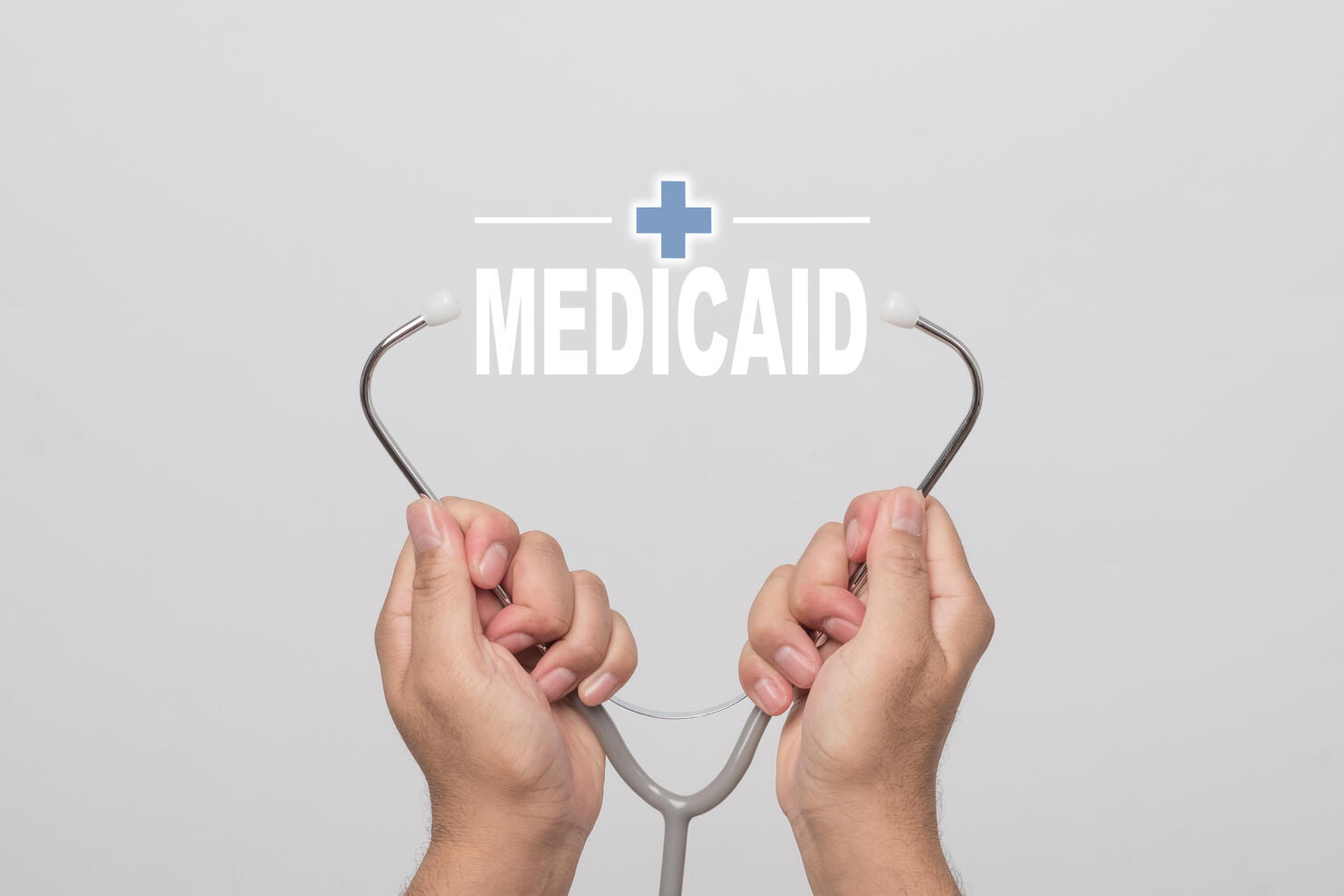 Hands holding a stethoscope and word "MEDICAID"  medical concept.