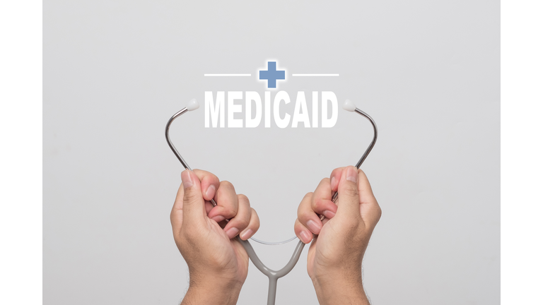 Hands holding a stethoscope and word "MEDICAID"  medical concept.