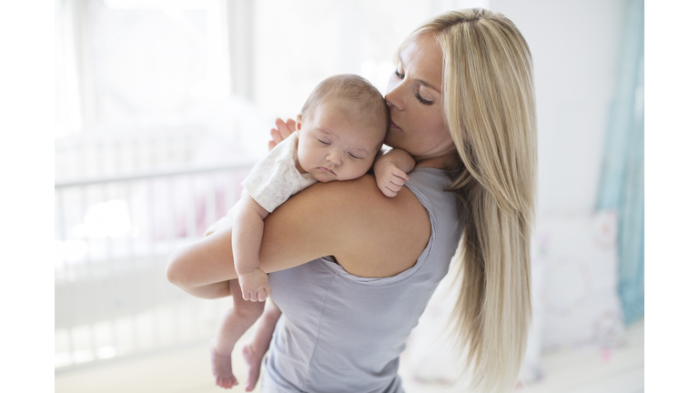 Mother carrying sleeping baby girl