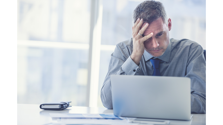 Stressed mature businessman with laptop.