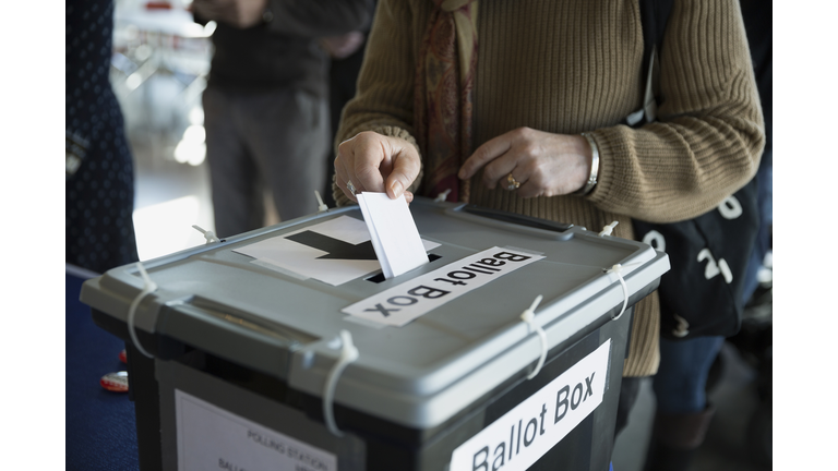 Woman placing ballot in ballot box polling place