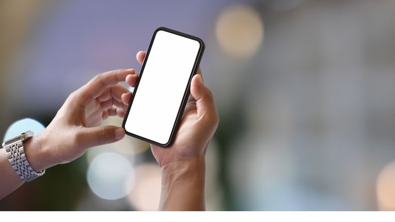 Man hands holding blank screen smartphone with blurred light bokeh background