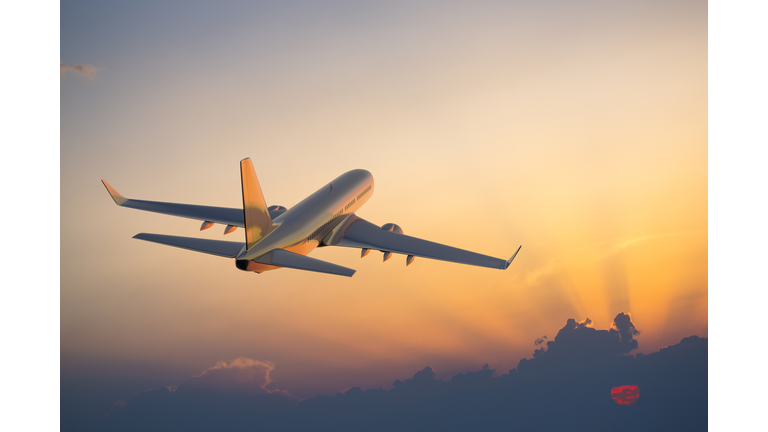 Passenger airplane flying above clouds during sunset