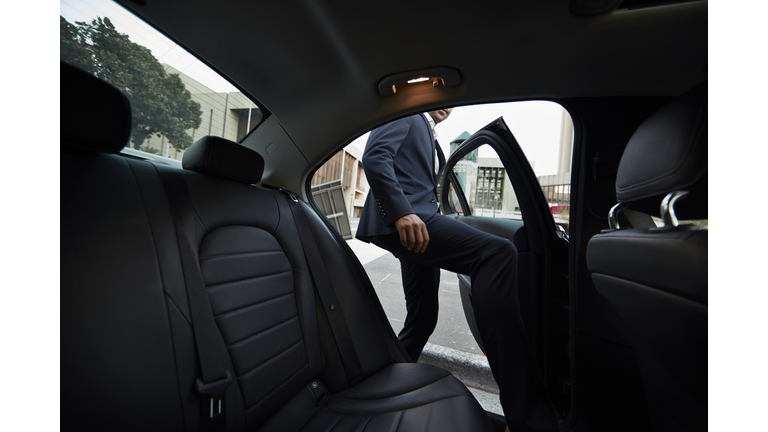 Businessman getting into backseat of exclusive cab