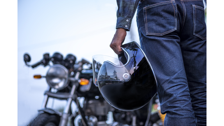 biker riding wear jeans with helmet and classic motorcycle blur background