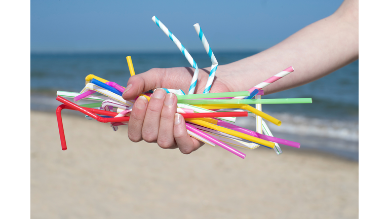 Close Up Of Hand Holding Plastic Straws Polluting Beach