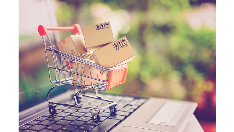 Online shopping and delivery service concept. Paper cartons in a shopping cart on a laptop keyboard, this image implies online shopping that customer order things from retailer sites via the internet.