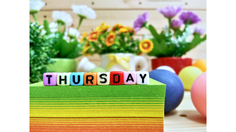 Close-Up Of Colorful Blocks With Thursday Text On Stacked Papers Over Table