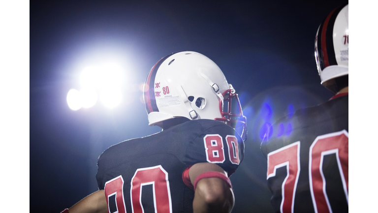 Low angle view of American football players against sky at night