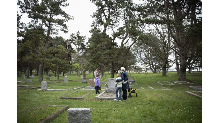 Multi-generation women visiting gravesite in cemetery