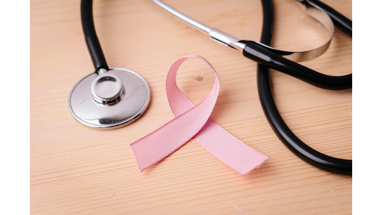 Close-Up Of Pink Breast Cancer Ribbon By Stethoscope On Table