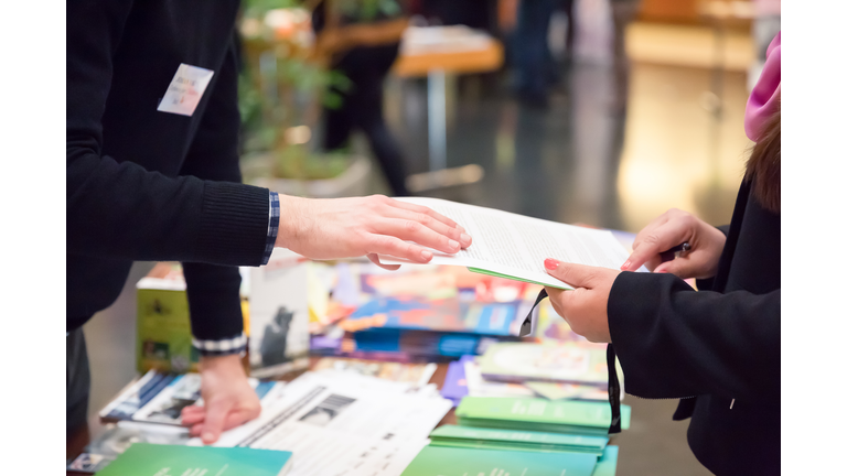 Man and Woman Sharing Information Leaflet over Exhibition Stand