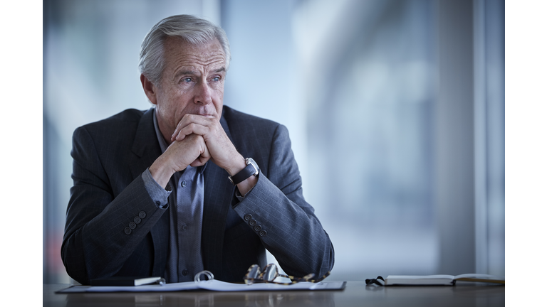 Pensive senior businessman looking away in conference room