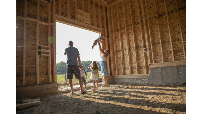 Young family standing in rural barn under construction