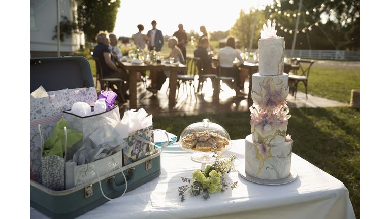 Tiered wedding cake, gifts and flowers on patio table