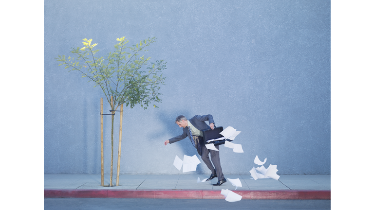 Businessman dropping papers from briefcase