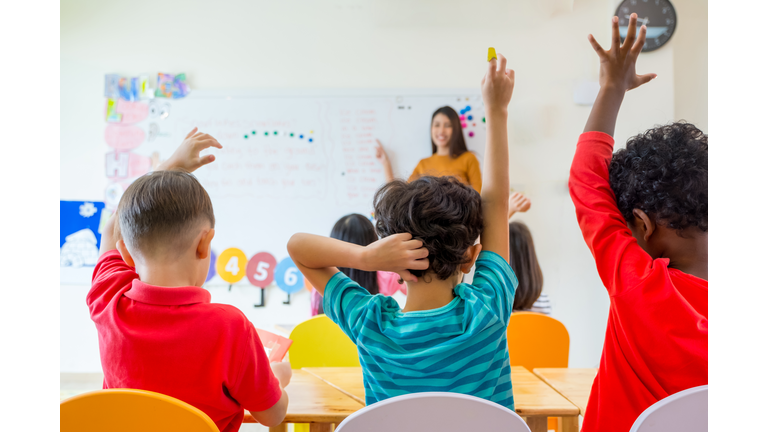 Rear View Of Students Sitting With Teacher