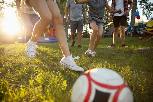 Family playing soccer in sunny park