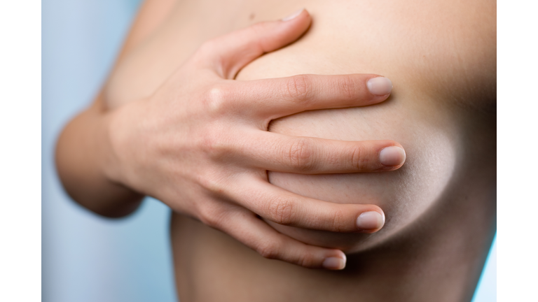 Close-up of a topless woman holding a hand over her breast