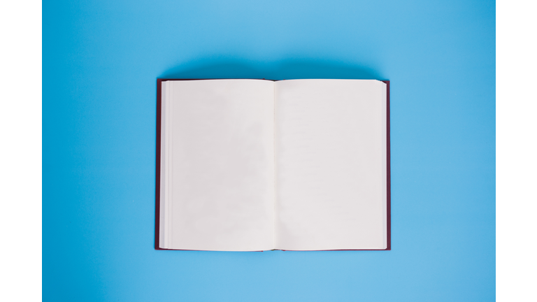 Directly Above Shot Of Open Book Against Blue Background