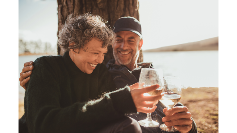 Relaxed mature couple having a glass of wine at campsite