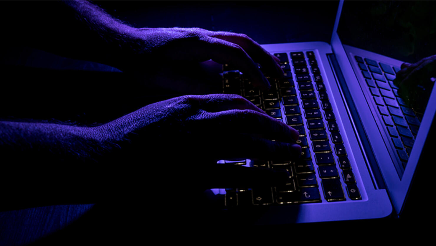 Cropped Hands Of Person Using Laptop On Table In Darkroom