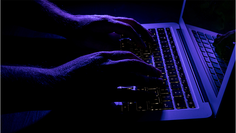 Cropped Hands Of Person Using Laptop On Table In Darkroom