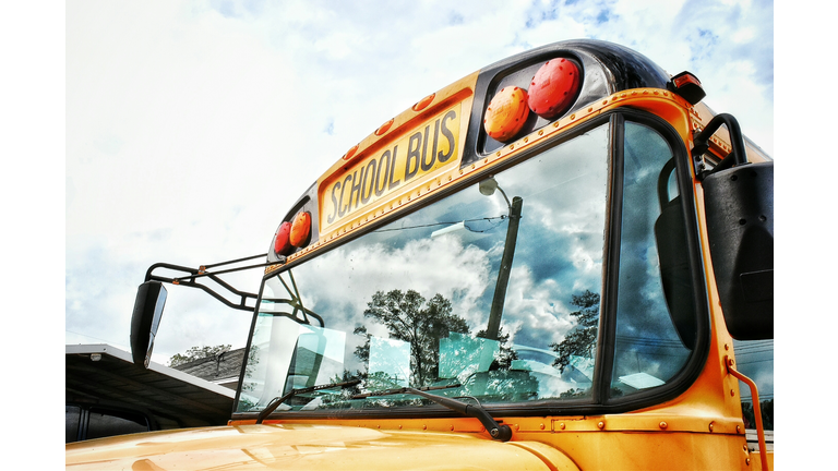 Close-Up High Section Of School Bus Against Clouds