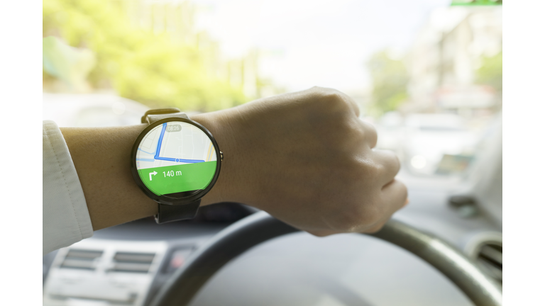 Close up of man in car on road watching smartwatch and using application navigation map to destination