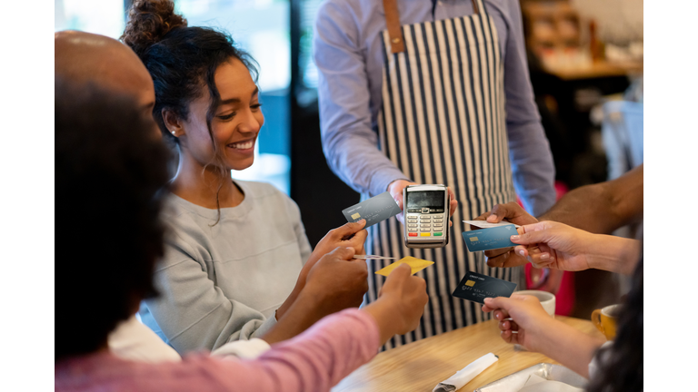 Group of friends paying with a credit card at a restaurant and splitting the bill