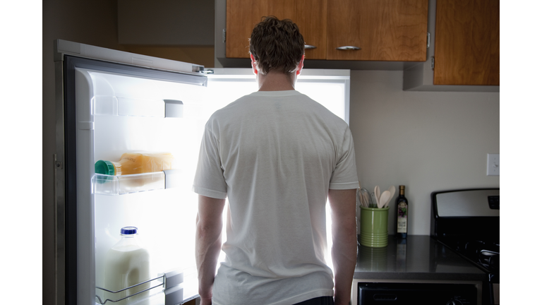Man standing looking at contents of fridge