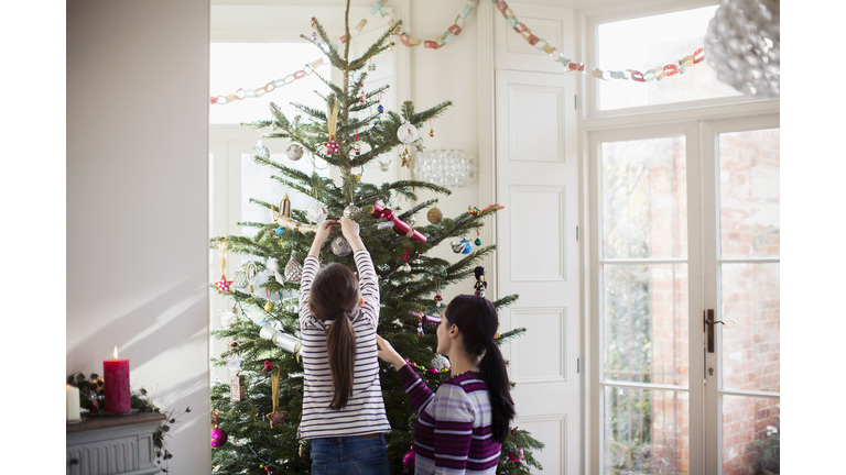 Mother and daughter decorating Christmas tree