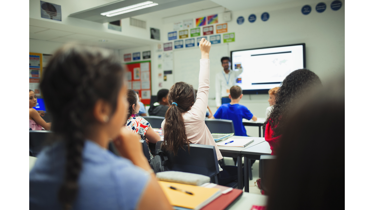 Junior high school student raising hand, asking a question during lesson in classroom