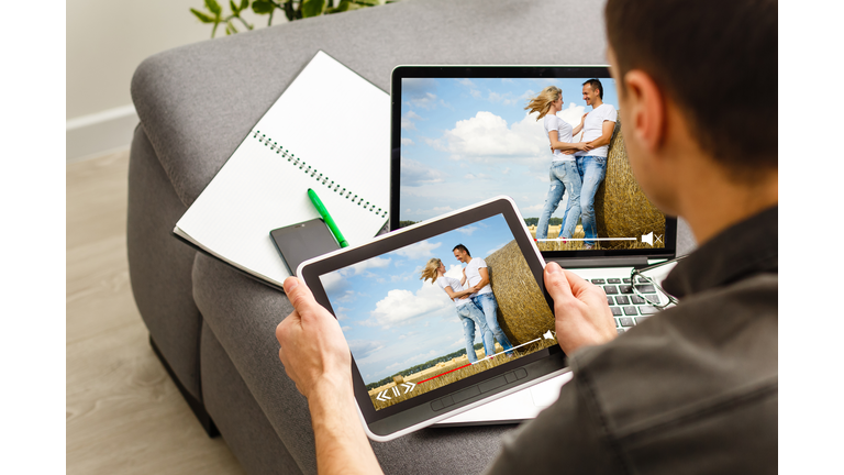 Online streaming concept: man using a laptop with online streaming website on the screen. Screen graphics are made up.
